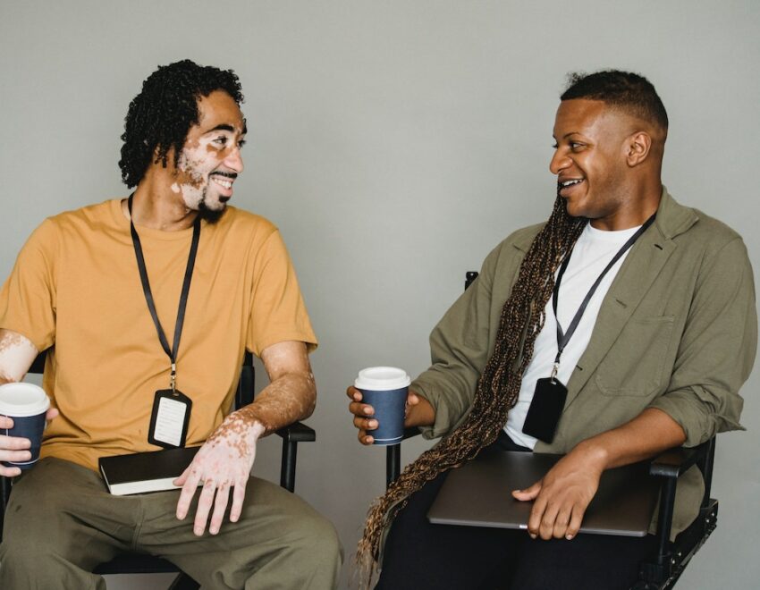 Two men drinking coffee and smiling at each other.