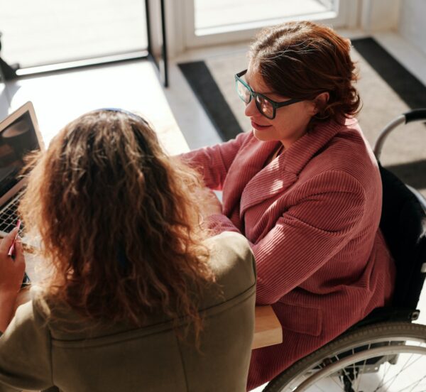 Two women working together around a laptop