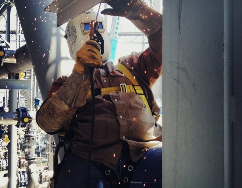 Man in protective equipment welding steel on a construction site.