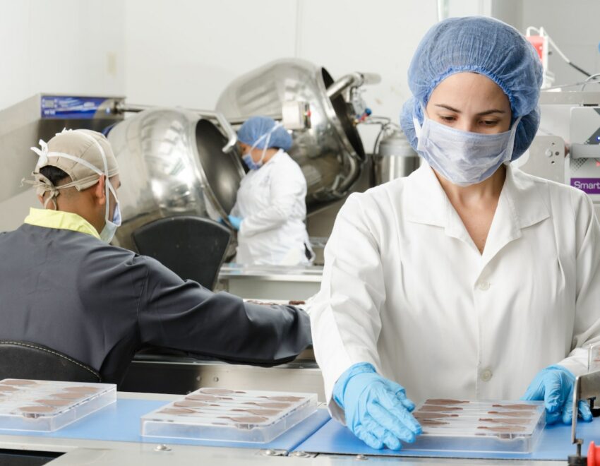 Woman in face mask, hair net and gloves working in a sterile environment