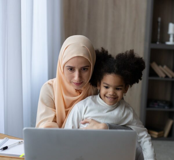 Mother working at laptop with daughter on her knee