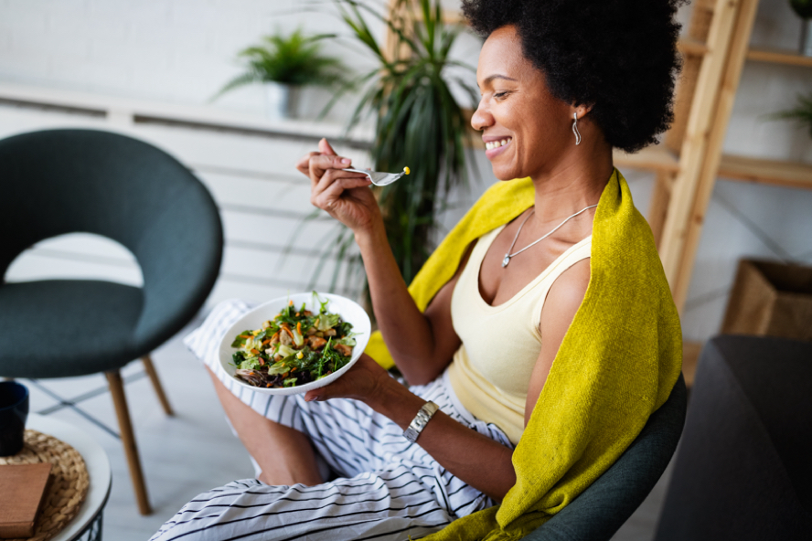 Woman enjoying eating a bowl of vegetable salad
