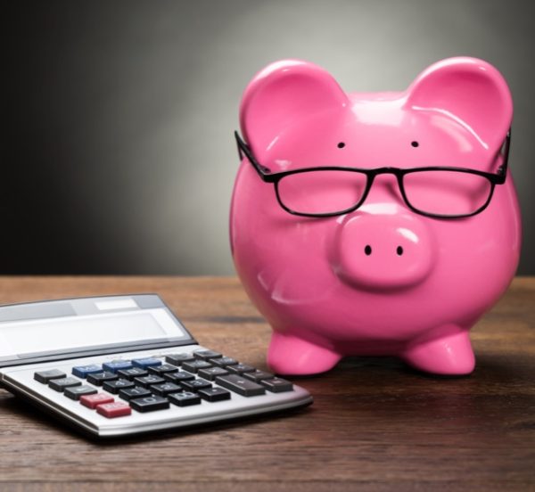 Pink piggybank and calculator on a wooden table