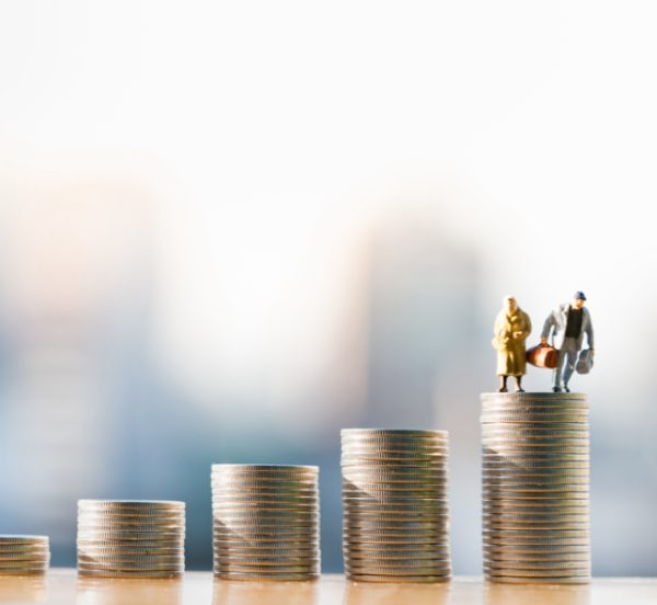 Miniature couple standing on top of coin stack