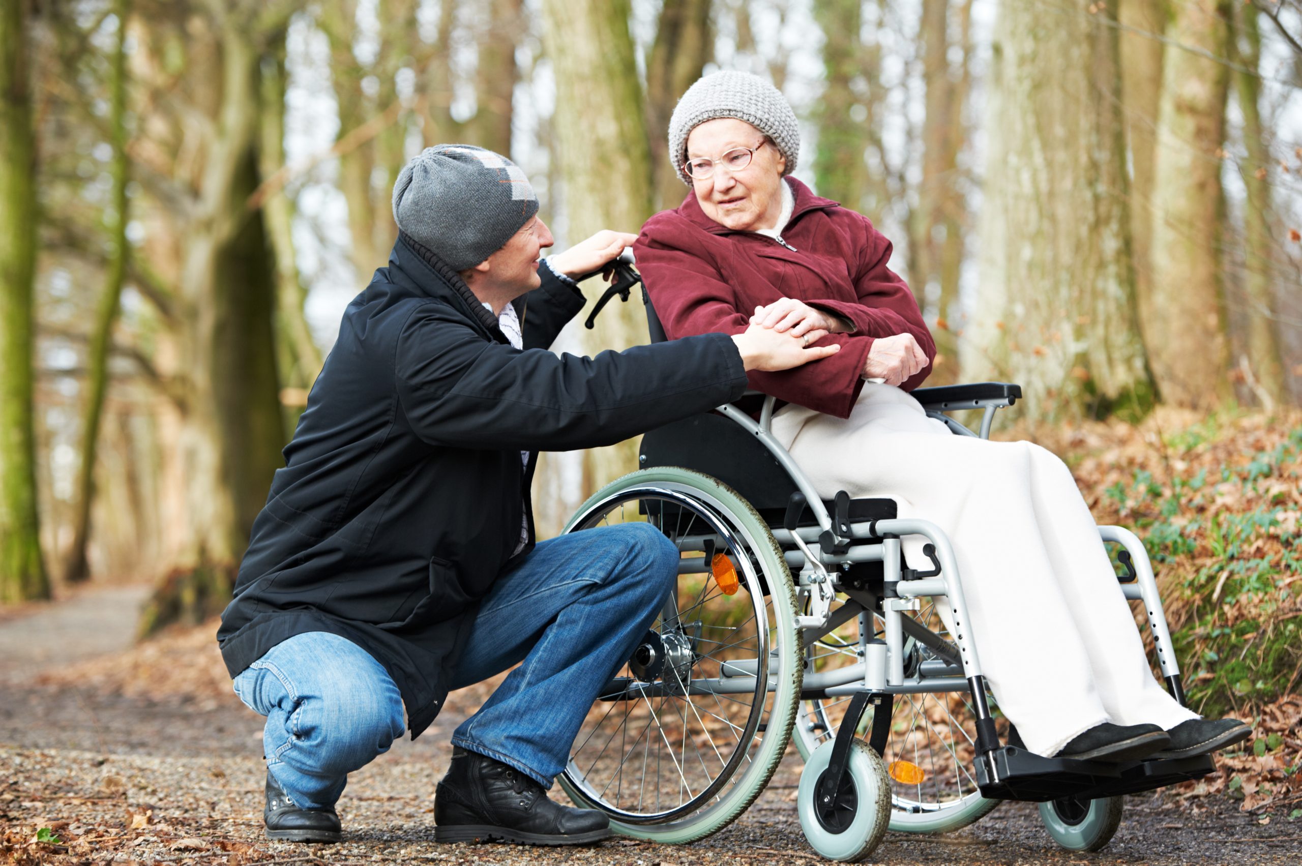 Man supporting an older woman who is in a wheel chair