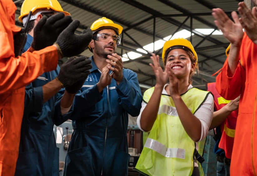 A man and a woman wearing hard hats and applauding